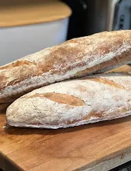 Two rustic baguettes resting on a wooden board